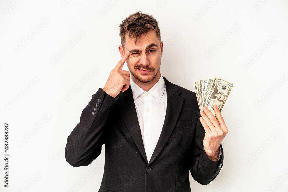 Young caucasian business man holding bank notes isolated on white background showing a disappointment gesture with forefinger. Young caucasian business man holding bank notes isolated on white background showing a disappointment gesture with forefinger.