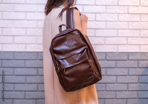 Woman holding brown leather backpack in the hand