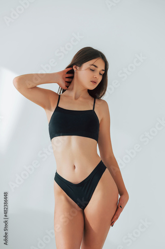 Standing against white background. Beautiful woman in underwear is posing indoors © standret
