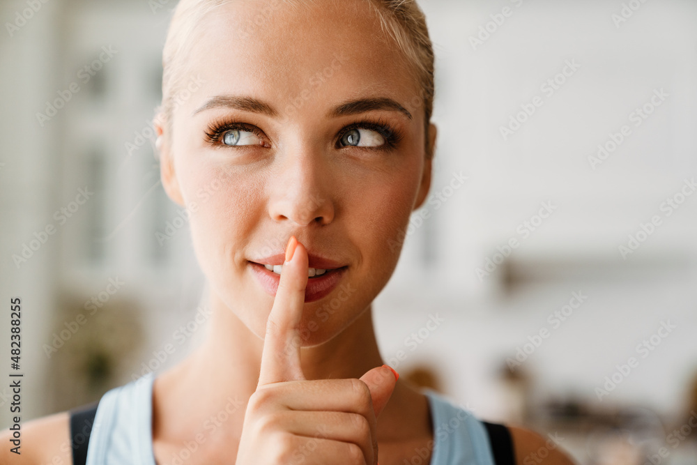 Blonde young woman showing silence gesture during yoga practice Blonde young woman showing silence gesture during yoga practice