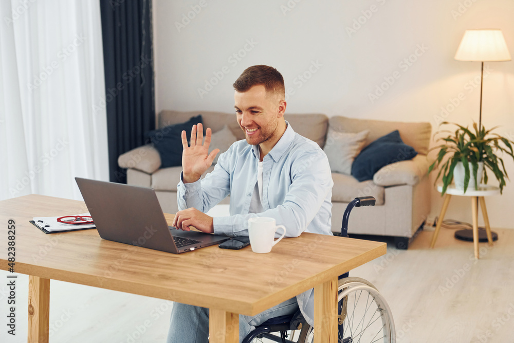 Laptop on the table. Disabled man in wheelchair is at home Laptop on the table. Disabled man in wheelchair is at home