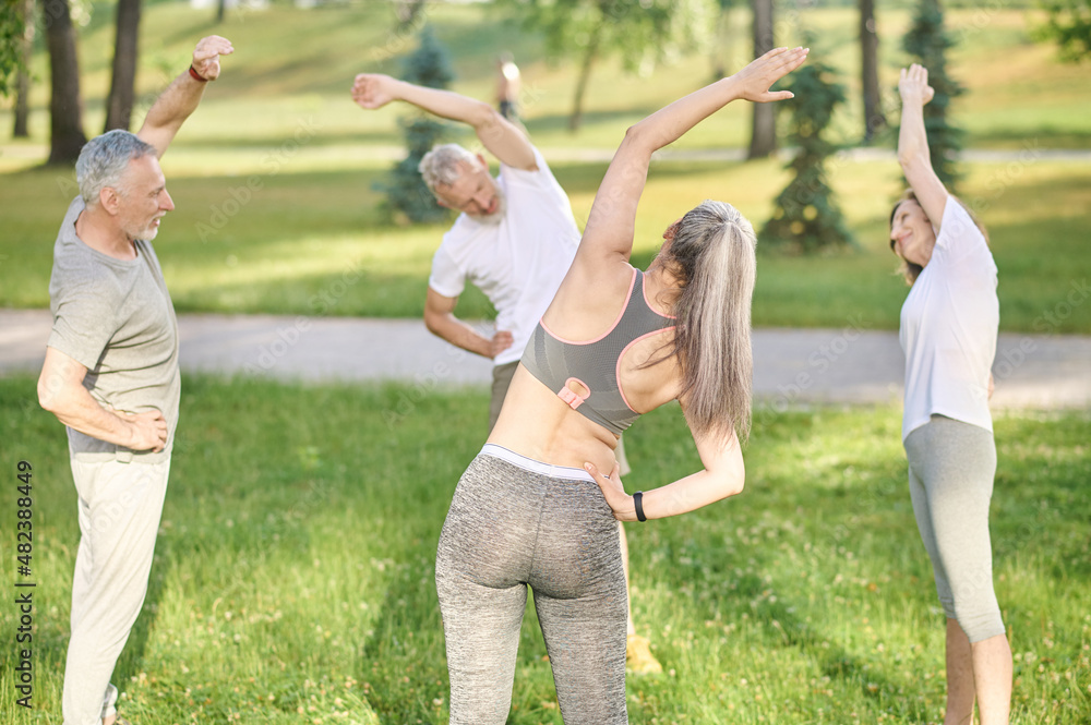 Obraz premium Group of people doing morning exercises in the park