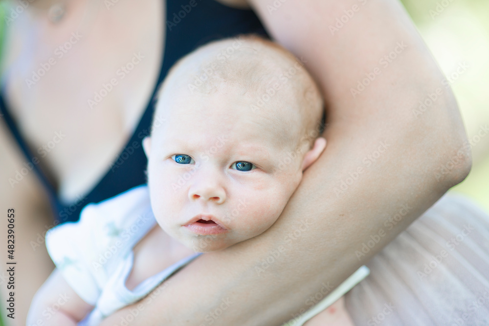 Close-up of a newborn baby's face, which the mother holds on her hands Close-up of a newborn baby's face, which the mother holds on her hands