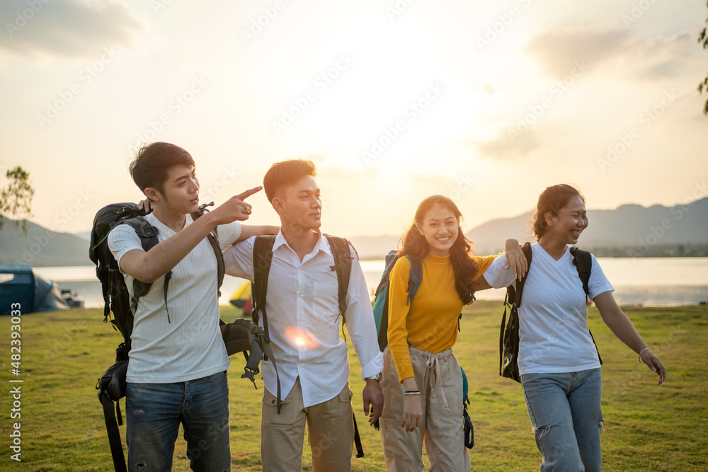 A group of Asian friends backpacking bag and walking for picnic and camping near lake A group of Asian friends backpacking bag and walking for picnic and camping near lake