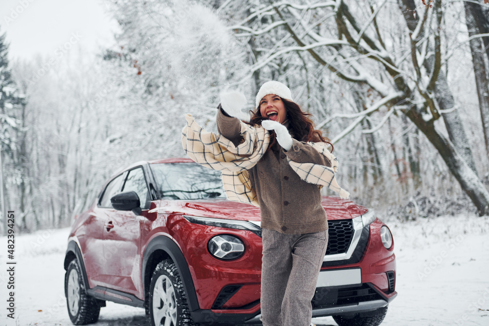 Beautiful nature. Young woman is outdoors near her red automobile at winter time