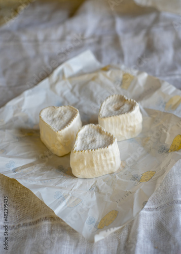 Heart-shaped cheese with white mold on wrapping paper. Home production, natural products.