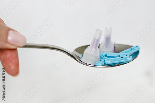 Blue lancets, needles with a spoon and scales on a white background