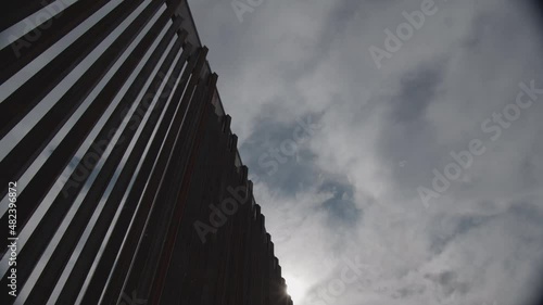 Low angle of the newly constructed border wall, clouds passby and the sun is just barely peeking through. photo