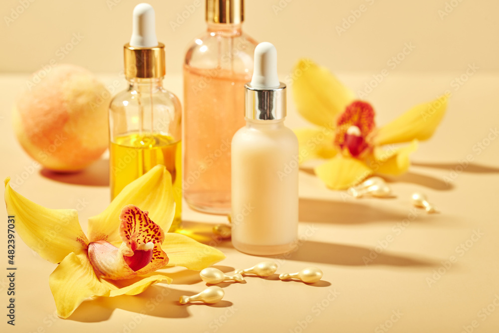 Cosmetic care products in glass bottles with orchid flowers - serums, cream, gel, oils. Concept for face and body care, wellness and spa, tropical relaxation. Cosmetic care products in glass bottles with orchid flowers - serums, cream, gel, oils. Concept for face and body care, wellness and spa, tropical relaxation.