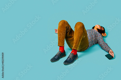 Photography man with a monkey mask and a smartphone lying down