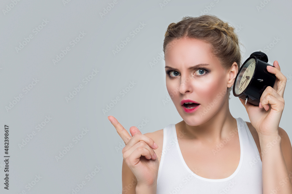 Youth Lifestyle Concepts. Young Stressfull Caucasian Female With Alarm Clock And Lifted Point Finger on Face. Youth Lifestyle Concepts. Young Stressfull Caucasian Female With Alarm Clock And Lifted Point Finger on Face.