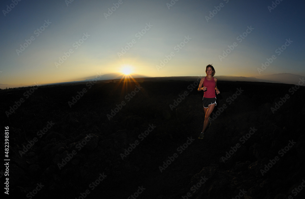 Woman jogger over lava field at sunrise, Big Island, Hawaii, USA, MR