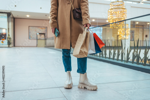 Close-up of a woman holding shopping for colorful shopping bags in a mall .A close-up shot of a young woman with colorful shopping bags while walking through a mall. Shopping concept.