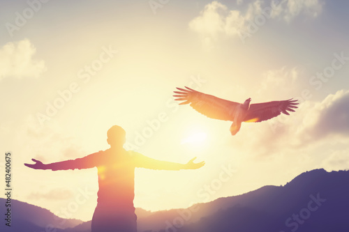 Man raise hand up on top of mountain and sunset sky with eagle birds fly abstract background.