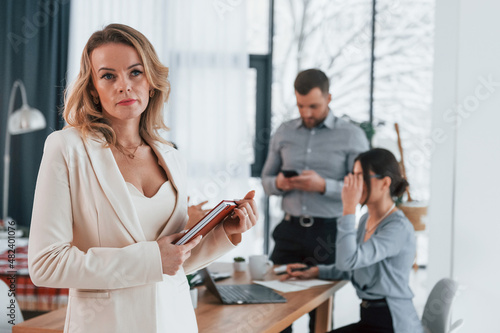 Woman in white clothes standing in front of her employees. Group of business people that working on the project in the office