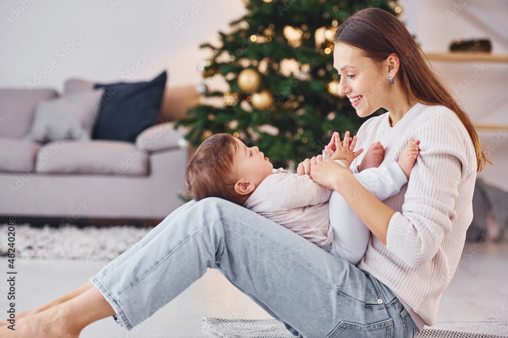 Playing with each other. Mother with her little daughter is indoors at home together
