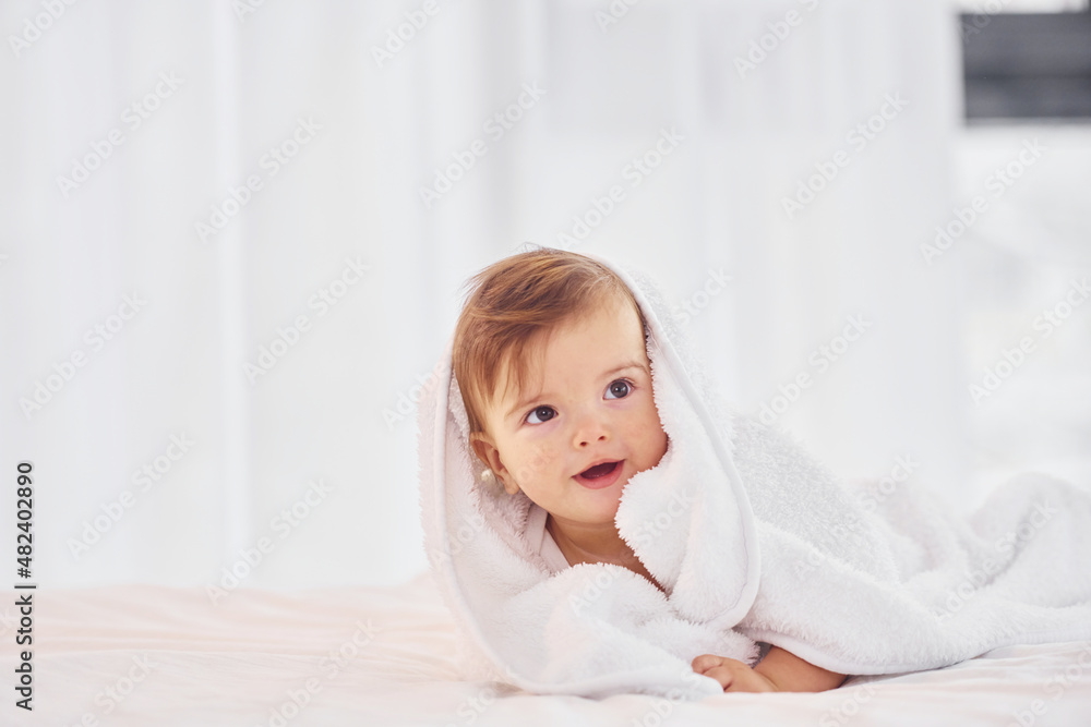 With white towel. Cute little baby is indoors in the domestic room With white towel. Cute little baby is indoors in the domestic room