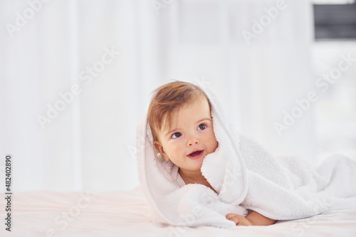 With white towel. Cute little baby is indoors in the domestic room