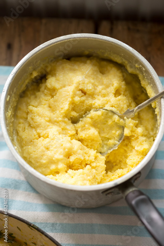 Cooked polenta dish, with parmesan, butter, salt and pepper . Polenta is made when cornmeal is boiled in water and chicken stock.