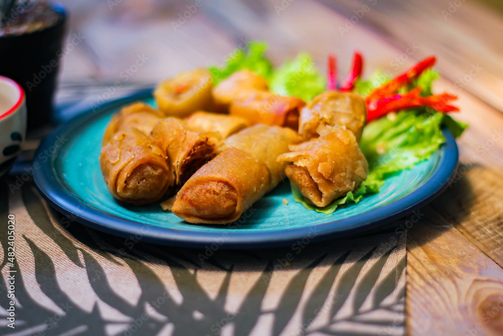 Deep fried spring rolls in blue plates with vegetables, chili and dipping sauce (Chinese food)