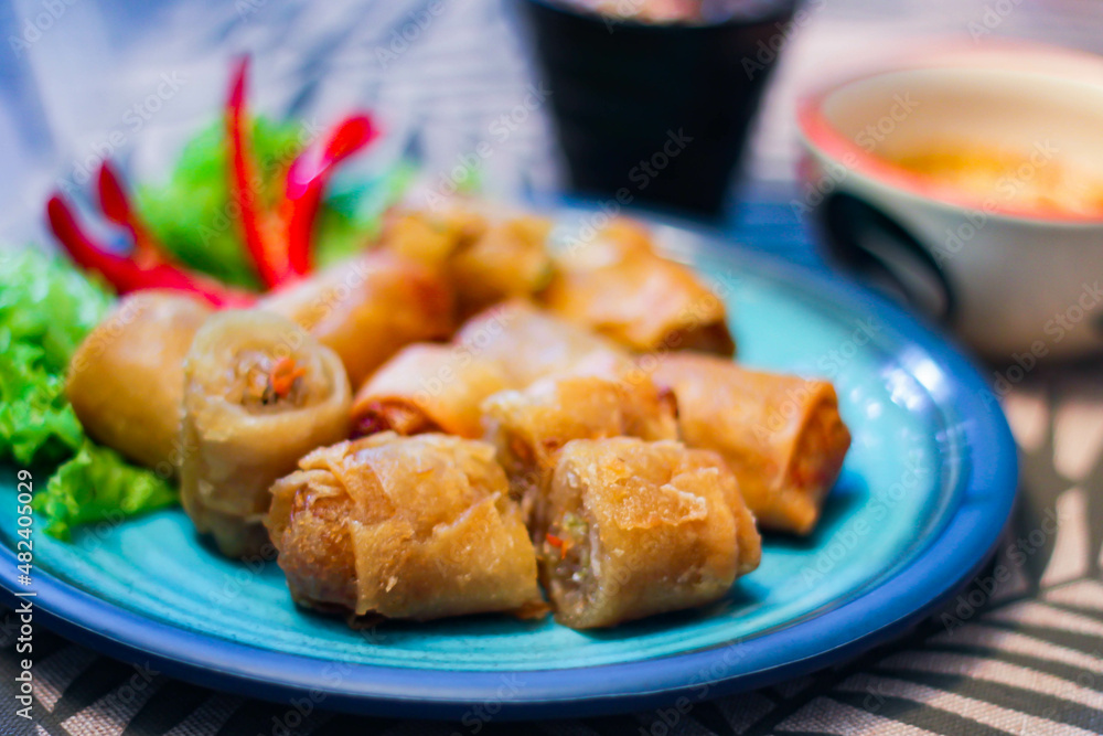 Deep fried spring rolls in blue plates with vegetables, chili and dipping sauce (Chinese food) Deep fried spring rolls in blue plates with vegetables, chili and dipping sauce (Chinese food)