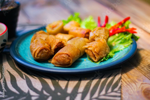 Deep fried spring rolls in blue plates with vegetables, chili and dipping sauce (Chinese food)