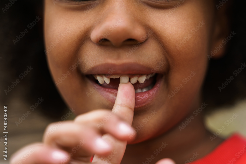 Black curly boy laughing while biting his finger outdoors Black curly boy laughing while biting his finger outdoors