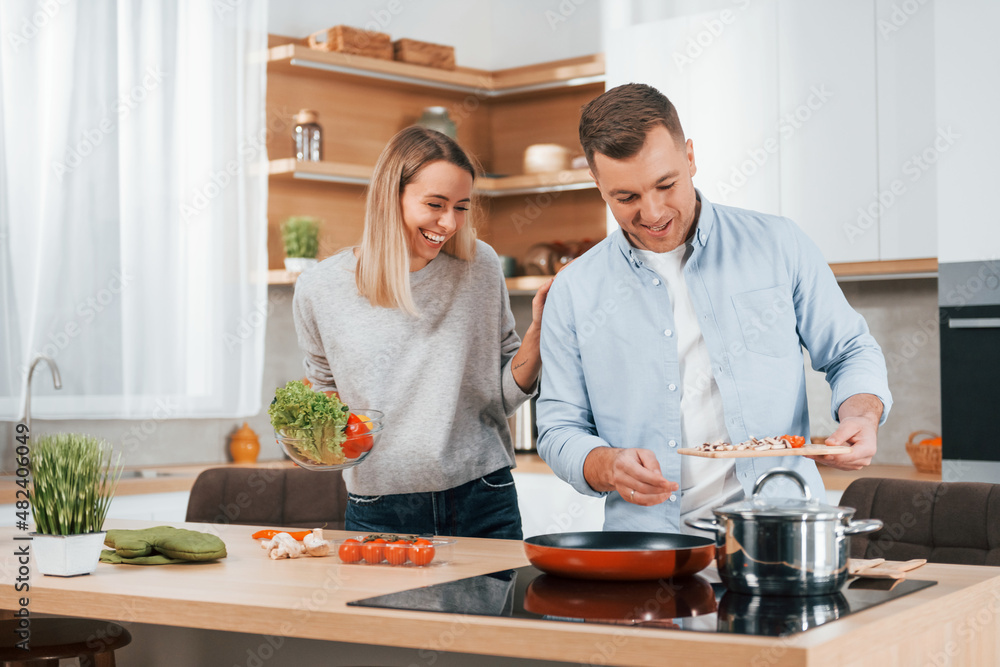Man standing by the table. Couple preparing food at home on the modern kitchen Man standing by the table. Couple preparing food at home on the modern kitchen