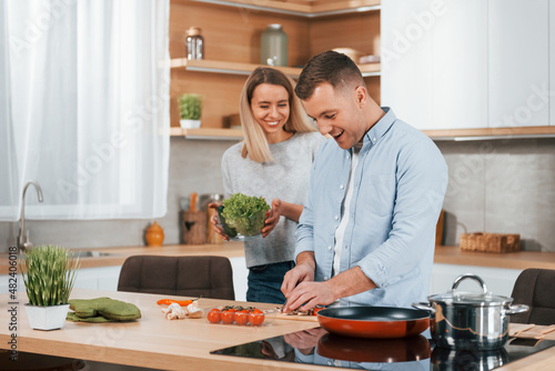 Man standing by the table. Couple preparing food at home on the modern kitchen