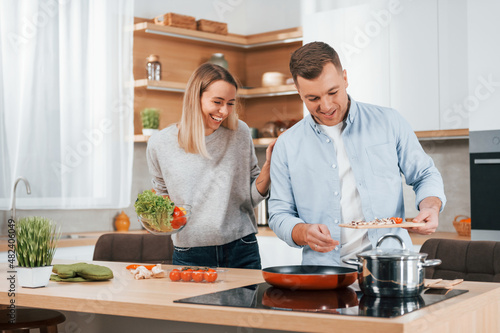 Man standing by the table. Couple preparing food at home on the modern kitchen