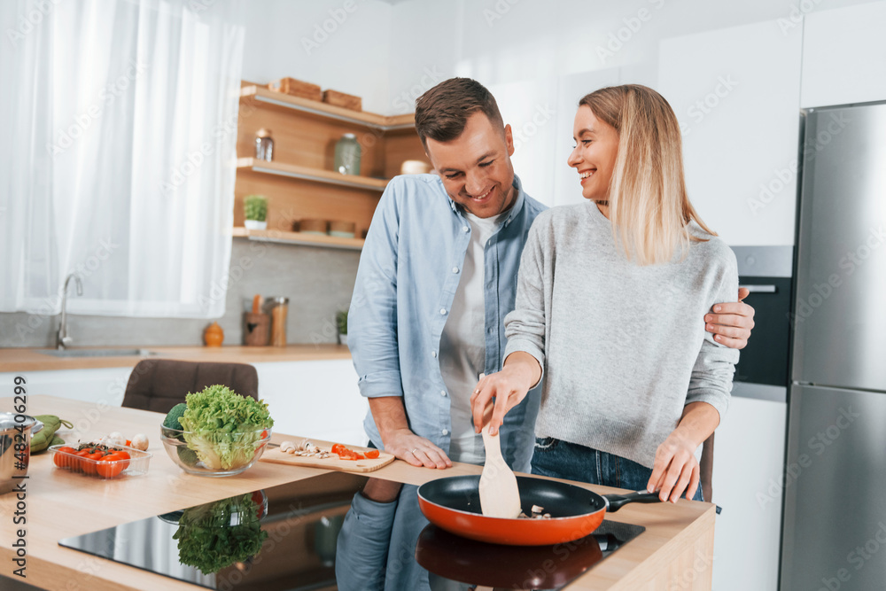 Frying food in a pan. Couple preparing food at home on the modern kitchen