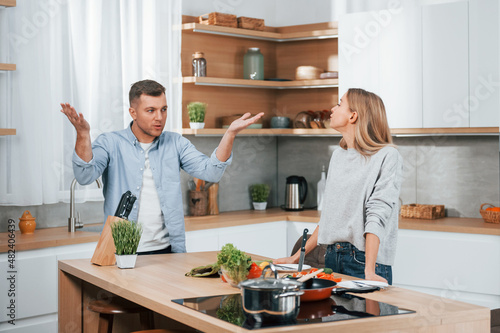 Screaming and arguing with each other. Couple preparing food at home on the modern kitchen
