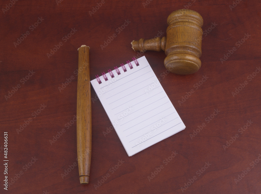 Notepad with pen and broken judge gavel.	