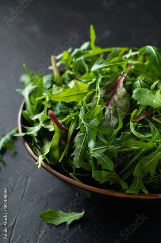 Mix salad greens. Arugula, lettuce, spinach in black bowl