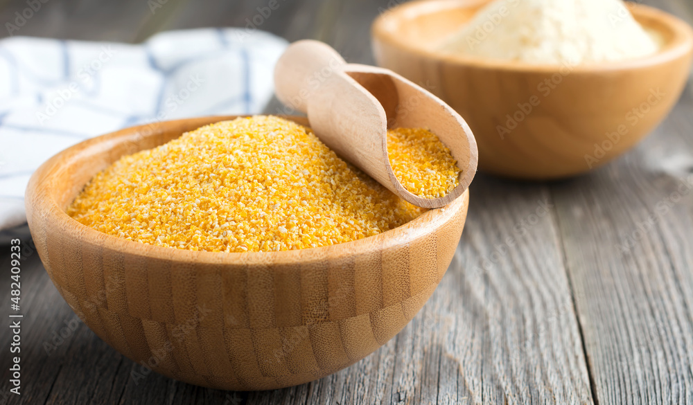Raw corn grits polenta in a bamboo bowl on the old wooden background. Selective focus Raw corn grits polenta in a bamboo bowl on the old wooden background. Selective focus