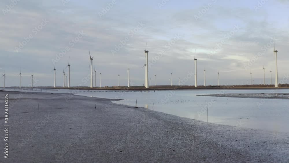 Windfarm near tidal area and dyke protecting adjacent polder from sea Windfarm near tidal area and dyke protecting adjacent polder from sea