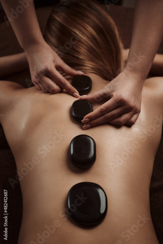 Woman getting spa treatment. Hot stone therapy. Top view. 