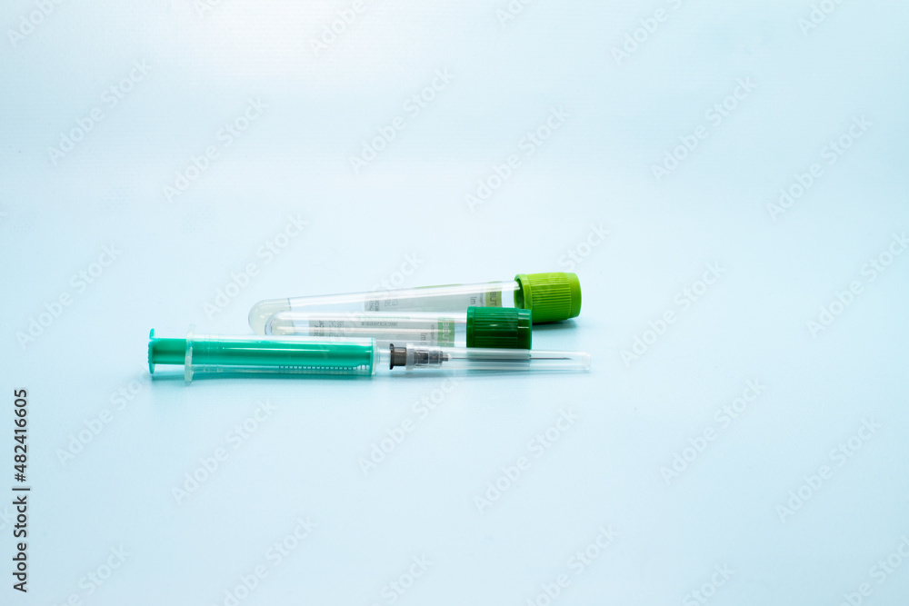 Two vacuum tubes for collection and blood samples and syringe on blue background for laboratory Two vacuum tubes for collection and blood samples and syringe on blue background for laboratory