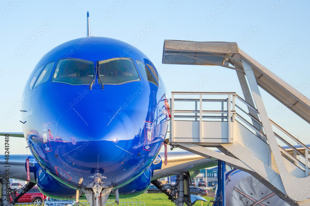 The cockpit and blue nose of the fuselage of the aircraft parked at the airport.