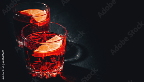 Two glass of cold alcohol cocktail drink on black background with copyspace. Negroni cocktail with orange on a black background.