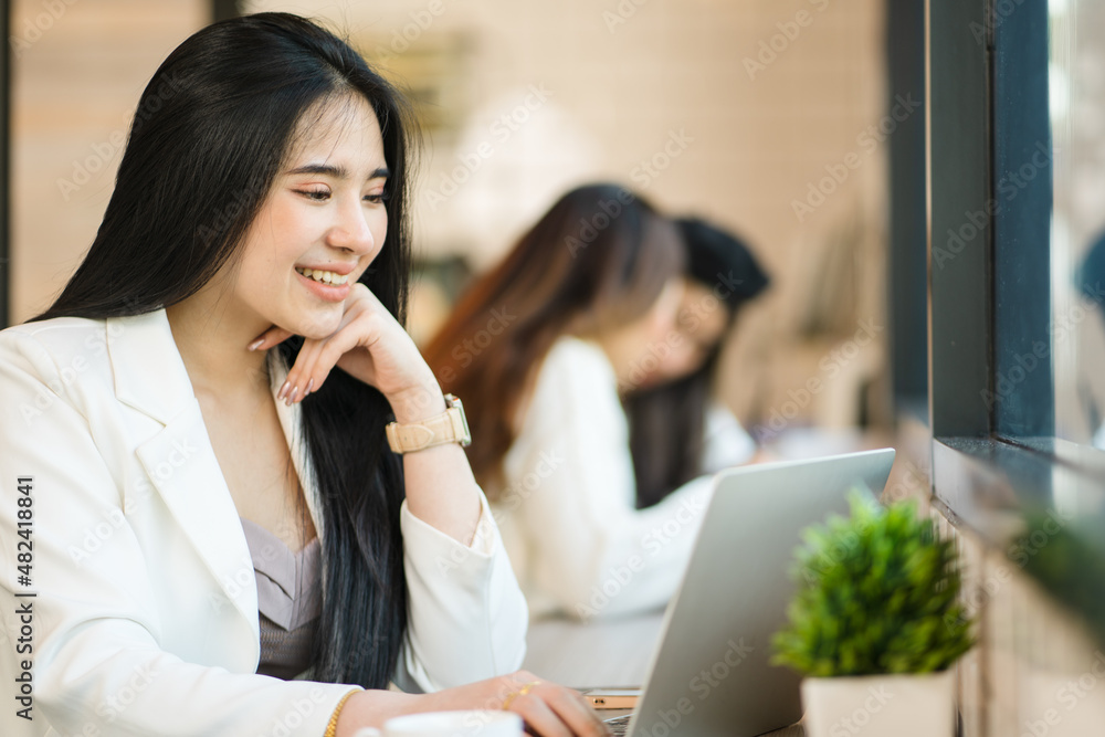 Happy young Asian entrepreneur using computer and staring at screen. Smiling female professional works in the internet, typing email and chatting online network Happy young Asian entrepreneur using computer and staring at screen. Smiling female professional works in the internet, typing email and chatting online network