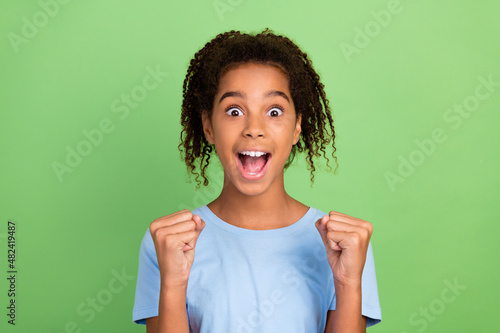 Photo of young excited afro girl happy positive smile rejoice victory success fists hands isolated over green color background