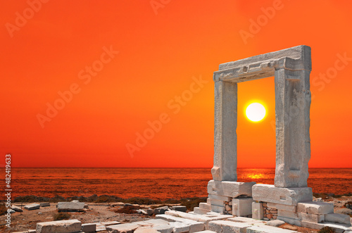 greece greek ancient temple huge gate of marble called "portara" in naxos island, sun in sunset orange colors