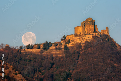 The Sacra di San Michele (Saint Michael Abbey) , the symbol of the Italian region of Piedmont, In the background the mountains of the Val di Susa with full moon.  photo