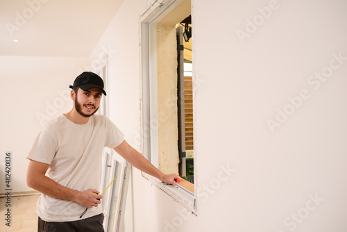 handsome young professional man installing and replacing a new home window in client house for improvement energy saving efficiency isolation