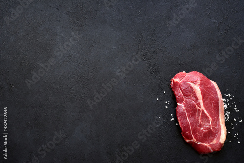 Raw organic beef steak with salt. Top view with copy space.