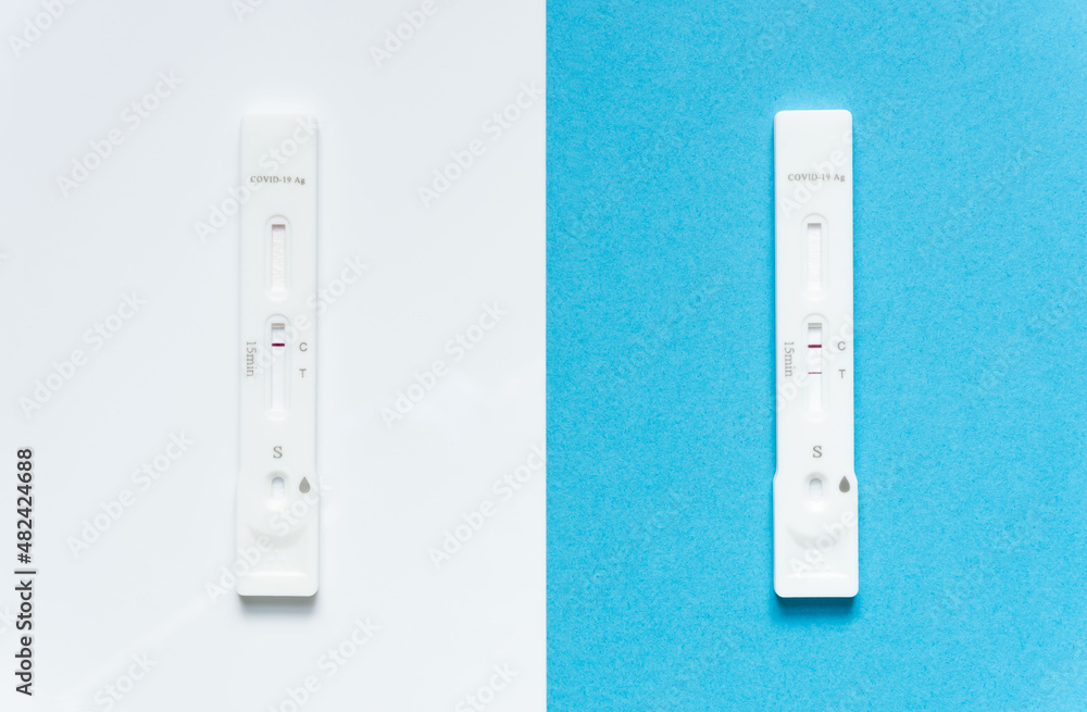 Rapid antigen tests for Covid-19 / SARS-CoV-2 infection concept, Omicron variant: 2 test kits with negative and positive result. Negative result on white background and blue background with positive Rapid antigen tests for Covid-19 / SARS-CoV-2 infection concept, Omicron variant: 2 test kits with negative and positive result. Negative result on white background and blue background with positive