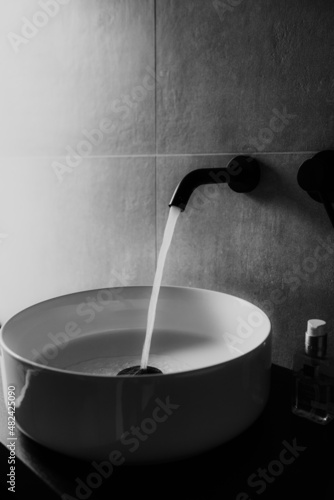 A running tap with washbasin in the bathroom.