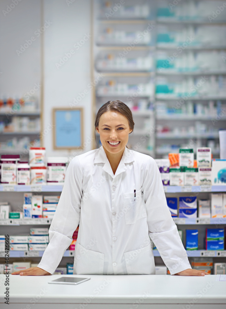 Providing prescriptions and a smile. Portrait of an attractive young pharmacist standing at the prescription counter. Providing prescriptions and a smile. Portrait of an attractive young pharmacist standing at the prescription counter.