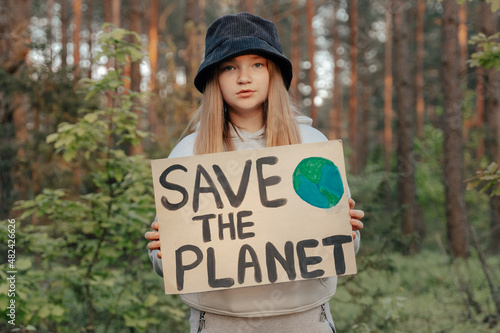 child girl activist with save the planet poster in forest park. preteen kid volunteer fight against pollution, Global Warming, recycle garbage. Ecology environmental problem